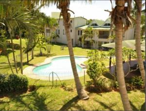 a swimming pool with palm trees in a resort at The Bridge Apartments Unit 35 in St Lucia