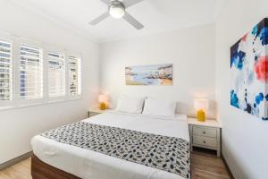 a white bedroom with a bed and two windows at Redvue Holiday Apartments in Redcliffe +122 photos
