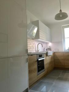 a white kitchen with a refrigerator and a sink at New apartment in Słupsk Downtown /Parking in Słupsk