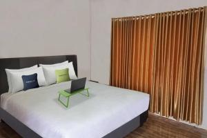 Urbanview Hotel Belitung Lodge Resto & Club House by RedDoorz في Simpangempat: غرفة نوم مع سرير مع لاب توب عليه