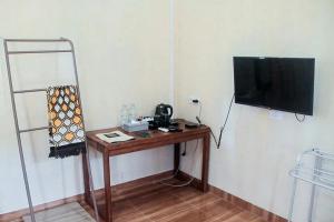 Habitación con mesa y TV en la pared. en Urbanview Hotel Belitung Lodge Resto & Club House by RedDoorz en Simpang Ampat