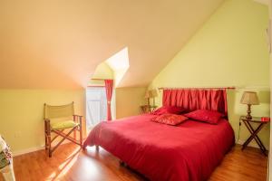 1 dormitorio con 1 cama roja y 1 silla en Le Chant des Oiseaux, en Trédion