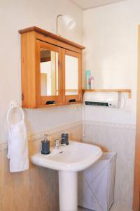 baño con lavabo blanco y armario de madera en El Apartamento de Trini, en Sevilla