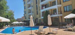 a woman sitting in a swimming pool next to a building at Golden Dreams Apartment in Sunny Beach