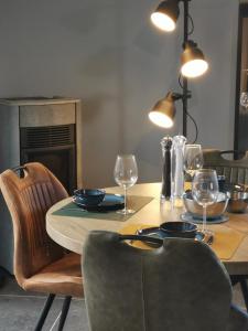 einen Esstisch mit Stühlen und einen Tisch mit Weingläsern in der Unterkunft Le Rougegorge 