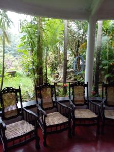 a porch with four chairs and a table and trees at Traditional Kandyan House in Kandy