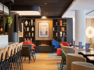 a restaurant with a fireplace and chairs and tables at Novotel Suites Paris CDG Airport Villepinte in Roissy-en-France