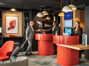 Novotel Suites Paris CDG Airport Villepinte في رواسي أون فرانس: ثلاث اشخاص واقفين عند كاونتر في اللوبي