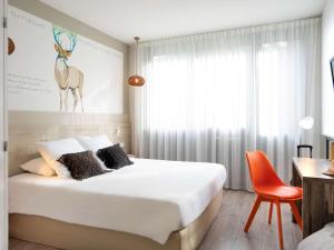 - une chambre avec un lit, un bureau et une chaise dans l'établissement ibis Styles Rennes St. Gregoire, à Saint-Grégoire