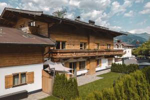 a large wooden house with a balcony and a yard at Mocking Ferienappartements in Kitzbühel