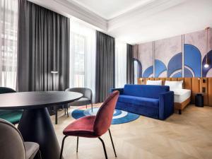 Habitación de hotel con sofá azul y mesa en Mercure Krakow Fabryczna City, en Cracovia