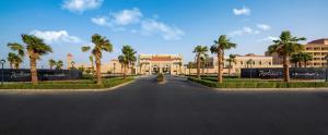 une rue en face d'un bâtiment avec des palmiers dans l'établissement Radisson Hotel Riyadh Airport, à Riyad