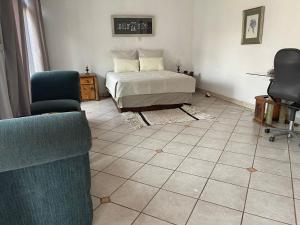 a bedroom with a bed and two chairs at Royal View Cottage in Hartbeespoort