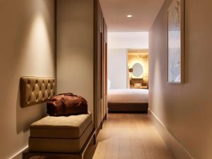 einen Flur mit einem Stuhl und einem Bett in einem Zimmer in der Unterkunft The Porter House Hotel Sydney - MGallery in Sydney