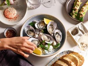 een persoon met een kom oesters op een tafel bij The Porter House Hotel Sydney - MGallery in Sydney