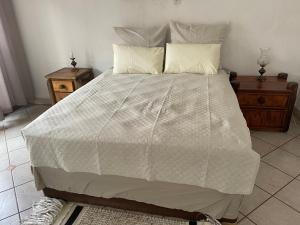 a bedroom with a large white bed with two pillows at Royal View Cottage in Hartbeespoort