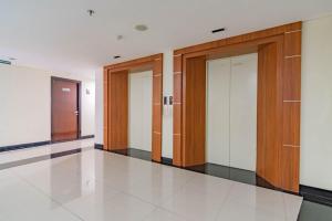 a row of elevators in a building with wooden doors at RedLiving Apartemen Gateway Pasteur - TN Hospitality 3 Tower Jade B in Bandung