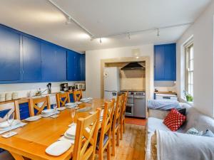 cocina y comedor con mesa de madera y armarios azules en The Wing At Brook Hall, en Newton Kyme