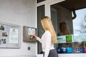 a woman is putting a key in a window at Gästehaus zur Linde in Ingolstadt