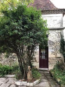 a stone house with a tree and a door at Gîte de L’Edelinie in Nanteuil-de-Bourzac