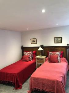 2 camas en una habitación con sábanas rojas y una lámpara en Gîte de L’Edelinie en Nanteuil-de-Bourzac