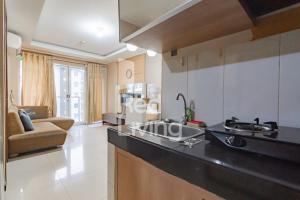 a kitchen with a sink and a living room at RedLiving Apartemen Gateway Pasteur - TN Hospitality 3 Tower Jade B in Bandung