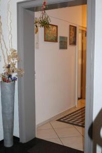 Un pasillo con un jarrón con flores. en HannoverCity Appartment, en Hannover