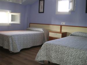a room with two beds and two windows at BAÑUGUES TURISMO S.L. in Bañugues