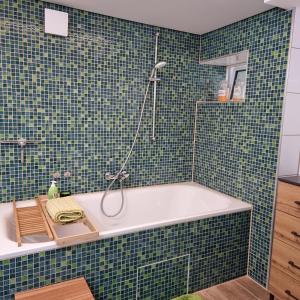 y baño con bañera y azulejos verdes. en Gästewohnung Detmerode, en Wolfsburg