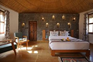 a bedroom with a large bed and a stone wall at Turban Nature Wilderness , Kumbhalgarh in Kumbhalgarh +50 photos