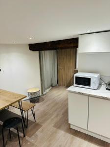 a kitchen with white cabinets and a table and a microwave at Gite le 16 in Ribeauvillé