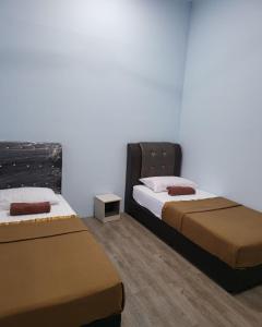 a bedroom with two beds and a white wall at IBAI COTTAGE KUALA TERENGGANU (HOMESTAY) in Kuala Terengganu