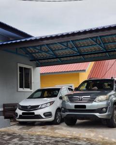 two cars are parked next to a building at IBAI COTTAGE KUALA TERENGGANU (HOMESTAY) in Kuala Terengganu