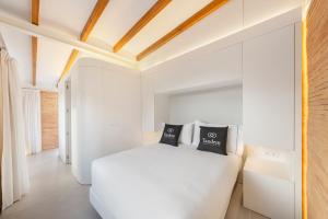 ein weißes Schlafzimmer mit einem weißen Bett und einem Sofa in der Unterkunft Tandem Pórtico Alicante Suites in Alicante