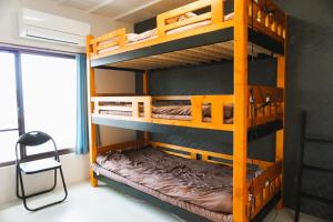 a bunk bed room with two bunk beds and a chair at ゲストハウス庵（いおり）大阪 in Fujiidera