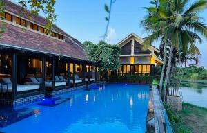a swimming pool in front of a house at THE BLOSSOM RESORT ISLAND - All Inclusive in Da Nang