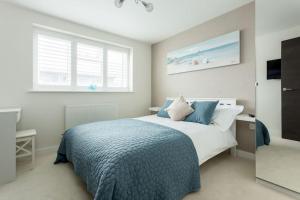 a bedroom with a bed with a blue blanket and a window at Stunning 2 bed apartment, fabulous sea view & 2 minutes to beach with parking in Southbourne