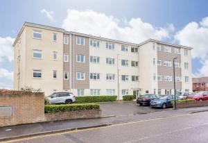 an apartment building with cars parked in a parking lot at Stunning 2 bed apartment, fabulous sea view & 2 minutes to beach with parking in Southbourne