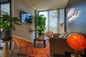 ein Wohnzimmer mit einem Sofa, Stühlen und einer Pflanze in der Unterkunft NYCE Hotel Ulm in Ulm