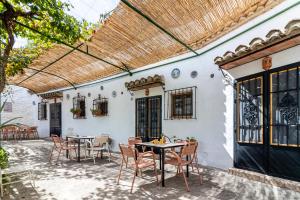 un patio con mesas, sillas y una pérgola en Cuevas El Abanico - VTAR vivienda turística de alojamiento rural en Granada