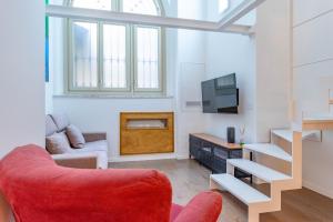 ein Wohnzimmer mit einem roten Stuhl und einem TV in der Unterkunft Dream Loft in Turin