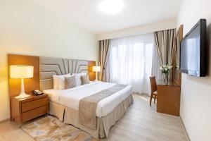 a hotel room with a bed and a flat screen tv at Golden Sands Suites in Dubai