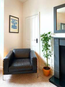a black leather couch in a living room with a plant at The Wee Bunk House - Innerleithen in Innerleithen
