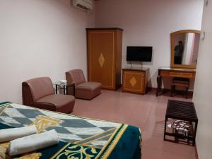 a bedroom with a bed and a desk and a television at Hotel Parewisata in Parepare