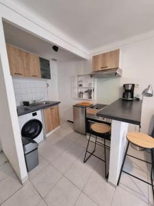 a kitchen with a sink and a counter with stools at Appartement coquet Le Boulou in Le Boulou