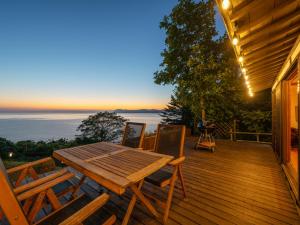 una terraza de madera con mesa y sillas de madera en Toya cliff House, en Lago Toya