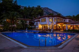 a large swimming pool in front of a house at night at Yucelen Hotel in Akyaka
