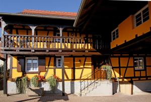 ein gelbes Gebäude mit einem Balkon und einer Treppe darauf in der Unterkunft Gîte Le Vendangeur in Donnenheim