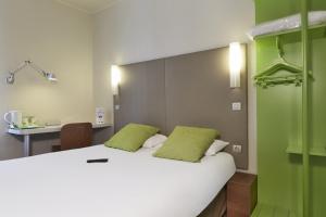 a bed with two green pillows in a room at Campanile Paris Ouest - Porte de Champerret Levallois in Levallois-Perret