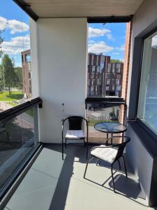 a balcony with two chairs and a table and windows at Professori in Joensuu